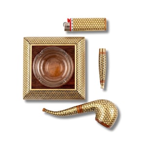 May include: A square wooden ashtray with a glass center, a rectangular lighter, a cylindrical tool, and a curved smoking pipe. Each item features a consistent gold and black geometric star pattern inlay against a dark brown wood base.