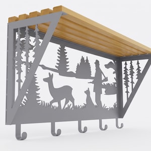 May include: A wall-mounted shelf with a light wood top and a grey metal frame featuring a laser-cut silhouette of a forest scene with a deer, a dog, and a person carrying a rifle. The frame includes five integrated hooks along the bottom edge.
