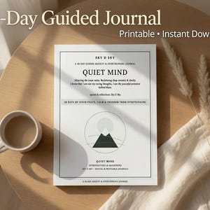 以下が含まれることがあります： Quiet Mindと題された黒いテキストが記載された白い長方形の30日間ガイド付きジャーナルページ。ページには山と太陽が描かれた円形のグラフィックがあり、Sky D Sky、A 30-Day Guided Anxiety & Overthinking Journal、30 Days of Inner Peace, Calm & Freedom From Overthinkingというテキストが含まれています。