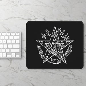 Könnte beinhalten: Ein rechteckiges schwarzes Mauspad mit einem weißen Tetragrammaton-Pentagramm-Aufdruck. Die Grafik zeigt einen zentralen Stern, verschiedene okkulte Symbole und hebräische Schriftzeichen, die kreisförmig um das Sternmotiv angeordnet sind.