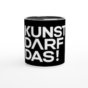 Könnte beinhalten: Ein schwarzer Keramikbecher mit dem weißen Schriftzug KUNST DARF DAS! in einer fetten, serifenlosen Schriftart. Der Becher hat eine zylindrische Form mit glatter Oberfläche und zeigt den deutschen Satz in drei Zeilen auf der Vorderseite.