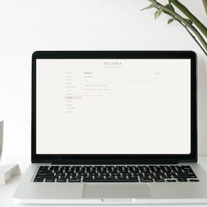 May include: A silver laptop displaying a digital interface with the text VELORA at the top, followed by a navigation menu on the left and a page titled Habits. The screen shows a task list with columns for days of the week and checkboxes.