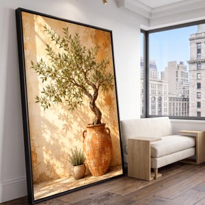 May include: A large framed wall art print featuring an olive tree planted in a tall, weathered terracotta urn with two handles, set against a textured, sun-drenched golden wall with a smaller potted plant resting on the ground beside the urn.