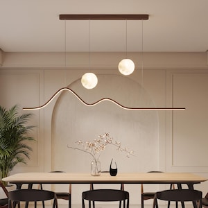 May include: A linear pendant light fixture featuring a dark brown horizontal bar with a gentle wave-like curve, suspended from a rectangular ceiling mount. Two glowing spherical orbs hang at different heights above the wavy light bar.
