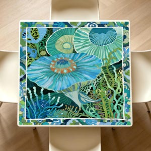 May include: A square table featuring a vibrant underwater-themed illustration with large blue and green jellyfish-like forms, intricate coral structures, and seaweed patterns. The design is framed by a decorative border of blue and green shapes.