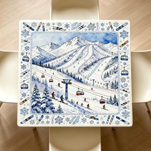 Peut inclure: Une table carrée présentant une illustration à l'aquarelle d'une station de ski enneigée avec des remontées mécaniques, des skieurs et des sapins. La bordure est ornée d'un motif répétitif de flocons, de skis et de snowboards sur fond blanc.