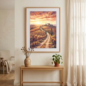 Könnte beinhalten: Ein gerahmter Ölgemäldedruck, der eine toskanische Landschaft bei Sonnenuntergang zeigt. Die Szene zeigt einen gewundenen Feldweg, der zu einer Villa auf einem Hügel führt, umgeben von goldenen Weinbergen und hohen Zypressen unter einem orangefarbenen Himmel.