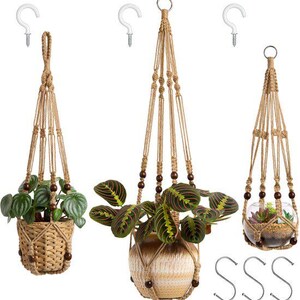 Op de afbeelding: Drie macramé plantenhangers van beige koord met donkerbruine houten kralen. De set bevat een gevlochten mand, een keramische pot met plant en een glazen kom met vetplant, vergezeld door drie witte plafondhaken en drie S-haken.