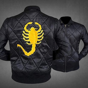 May include: A black quilted bomber jacket featuring a large, embroidered yellow scorpion on the back. The jacket has a ribbed collar, cuffs, and hem, with a full-length front zipper closure. The quilted pattern consists of diamond-shaped stitching.