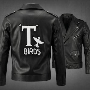 Könnte beinhalten: Eine schwarze Motorradjacke aus Leder mit einem großen weißen Aufnäher auf der Rückseite, der den Text T-BIRDS und eine Vogelgrafik zeigt. Die Jacke hat ein Revers, silberfarbene Reißverschlüsse, eine Vordertasche und einen Gürtel.