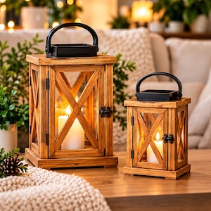 Peut inclure: Deux lanternes rectangulaires en bois avec une finition marron naturel, dotées d'un cadre en croix, de panneaux en verre et d'une poignée en métal noir sur le dessus. Chaque lanterne contient une bougie pilier blanche diffusant une lueur douce.
