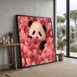 Può includere: Una stampa artistica incorniciata raffigurante un cucciolo di panda soffice immerso in un denso grappolo di fiori rosa vibranti e arrotondati. Il panda ha orecchie, macchie oculari e zampe nere che contrastano con i petali rosa dei fiori.