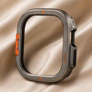 May include: A dark grey protective watch case with a rectangular frame. The case features bright orange accents on the side buttons, a small orange triangle at the top and bottom, and the word MODE printed in orange on the right side of the frame.