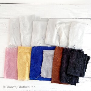 May include: A selection of fabric swatches in a range of colours, such as white, pink, yellow, blue, grey, brown, and black. The swatches are laid out on a white wooden surface. The image includes the text "Clare's Clothesline".