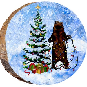 May include: A brown bear is tangled in Christmas lights in front of a snow-covered Christmas tree with colorful ornaments. The bear is standing on a snowy, blue background.