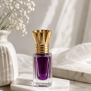 May include: A rectangular glass perfume bottle with a deep purple liquid interior and a metallic gold fluted cap. The bottle features clear glass sides and sits on a white marble surface. The text AREEBA DESIGN CO. is visible at the top.