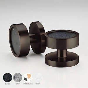 Pode incluir: Dois botões redondos de cor castanho escuro para armário com um design salpicado preto. Os botões têm uma base circular elevada e um caule cilíndrico.