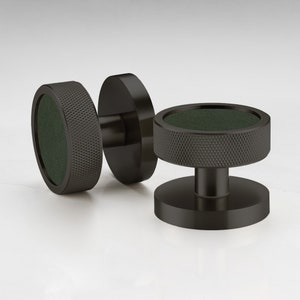 May include: Two black cabinet knobs with a green centre and a textured design.