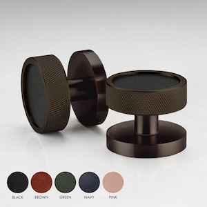 May include: Two dark brown metal cabinet knobs with a textured, circular design. The knobs have a black centre and a raised, textured edge.