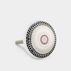 May include: White ceramic cabinet knob with a black and white geometric pattern and a pink center.
