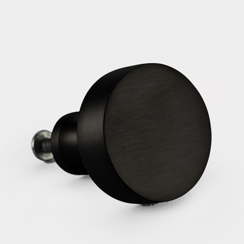 May include: Black round cabinet knob with a brushed finish.