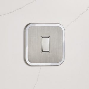 May include: A brushed nickel light switch with a white rocker and a silver trim.