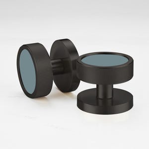 May include: Three black dumbbell weights with a circular design. The weights have a textured grip and a teal-colored center. The dumbbells are designed for strength training and fitness.