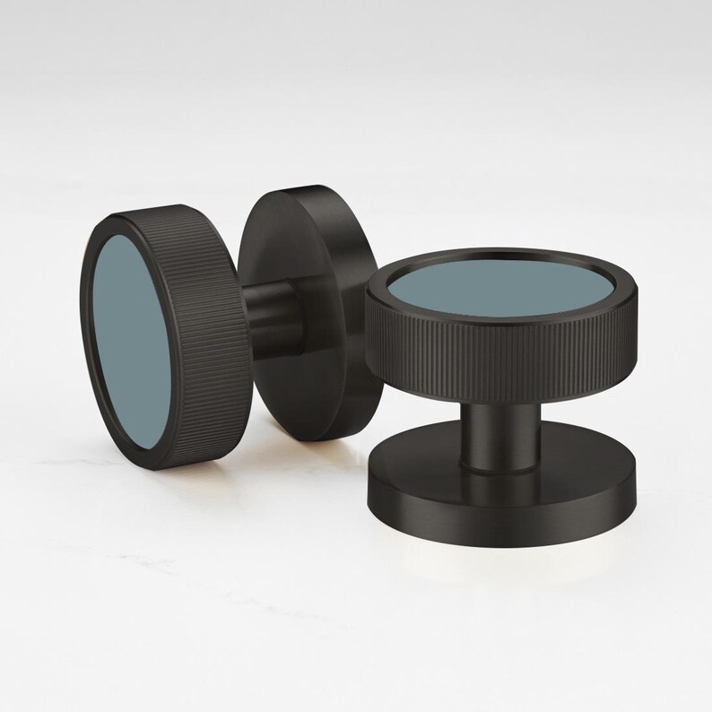 May include: Three black dumbbell weights with a circular design. The weights have a textured grip and a teal-colored center. The dumbbells are designed for strength training and fitness.