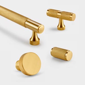 Peut inclure: Quatre boutons de porte en or texturés et moletés. Les boutons sont de formes différentes, notamment un bouton rond, un bouton barre et un bouton en forme de T.