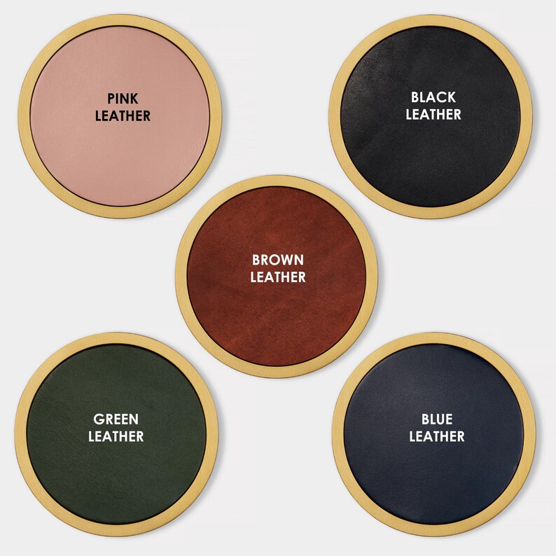 May include: Five round leather coasters in different colours: pink, black, brown, green, and blue. Each coaster has a gold rim and the colour of the leather is written in white text.