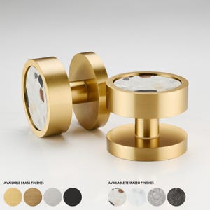 Peut inclure: Deux boutons de porte en laiton doré avec un motif rond en terrazzo blanc. Les boutons sont disponibles dans une variété de finitions en laiton et en terrazzo.