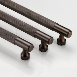 May include: Three different sizes of dark brown metal cabinet pulls with a textured, ridged design. The pulls have a round knob at the end.