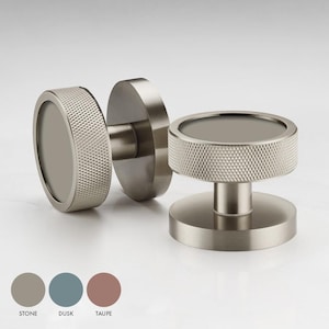 Pode incluir: Dois botões de armário prateados com um design circular texturizado. Os botões têm um centro circular elevado e uma base plana.