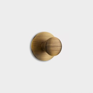 May include: A brushed gold round door knob with a circular base.