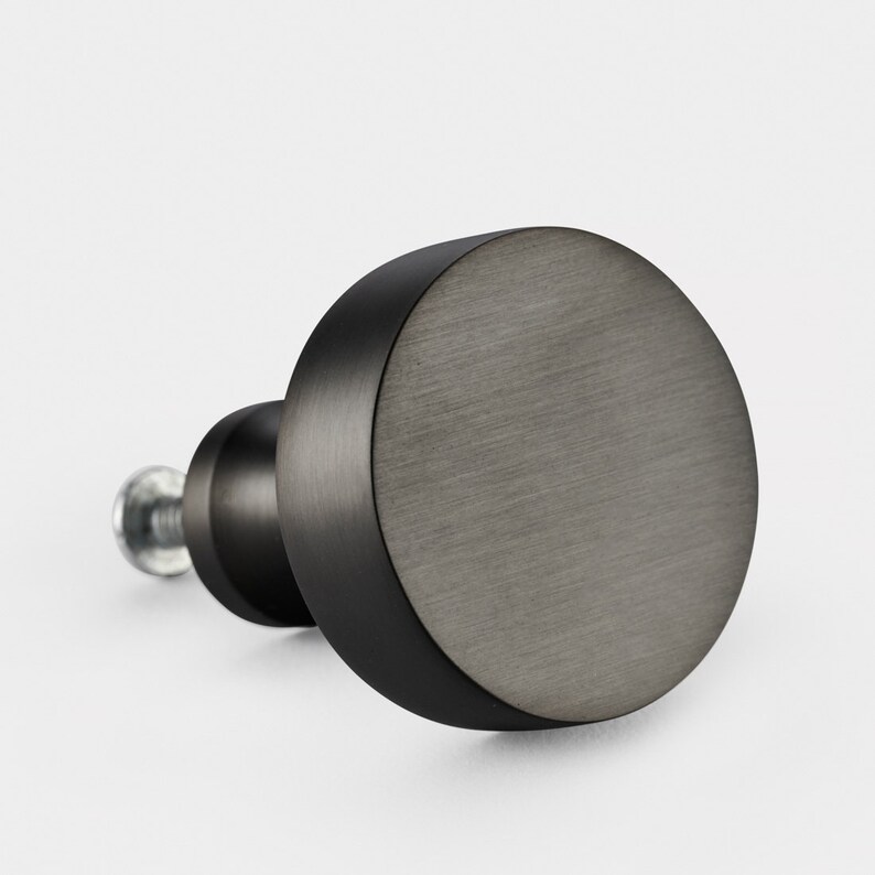 May include: A round black cabinet knob with a brushed metal finish.
