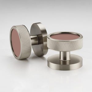 Puede incluir: Dos pomos de puerta de n&iacute;quel cepillado con un anillo exterior texturizado y un centro malva. Un pomo est&aacute; unido a una placa redonda, y el otro es un pomo independiente. Los pomos est&aacute;n dise&ntilde;ados para una est&eacute;tica moderna.