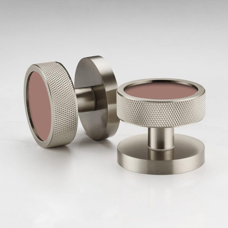 Puede incluir: Dos pomos de puerta de n&iacute;quel cepillado con un anillo exterior texturizado y un centro malva. Un pomo est&aacute; unido a una placa redonda, y el otro es un pomo independiente. Los pomos est&aacute;n dise&ntilde;ados para una est&eacute;tica moderna.