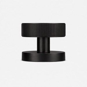 May include: A black, cylindrical door knob with a ridged top and a circular base. The knob has a minimalist design and is made of a matte black material. The door knob is suitable for interior doors.
