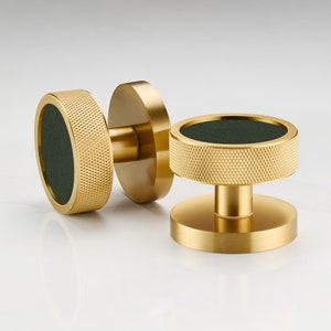 May include: Two gold cabinet knobs with a dark green centre. The knobs have a textured, ridged surface.