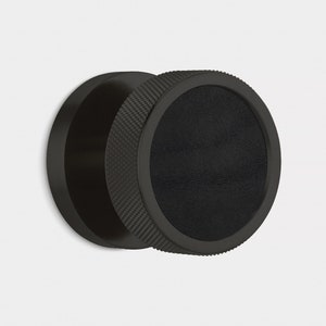 Peut inclure: Bouton de meuble noir circulaire avec une poign&eacute;e textur&eacute;e et un centre lisse et sombre. Le bouton est en mat&eacute;riau noir mat. Le design est moderne et minimaliste. Le bouton est de forme circulaire et con&ccedil;u pour une utilisation facile.