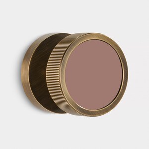 K&ouml;nnte beinhalten: Ein runder Wandspiegel in antik-messingfarbenem Finish. Der Spiegel hat ein mauvefarbenes Glas und einen geriffelten Rahmen. Der Spiegel ist an einer wei&szlig;en Wand befestigt. Der Durchmesser betr&auml;gt ca. 15 cm.