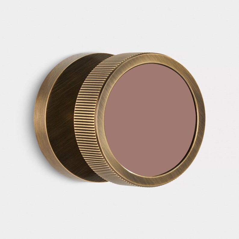 K&ouml;nnte beinhalten: Ein runder Wandspiegel in antik-messingfarbenem Finish. Der Spiegel hat ein mauvefarbenes Glas und einen geriffelten Rahmen. Der Spiegel ist an einer wei&szlig;en Wand befestigt. Der Durchmesser betr&auml;gt ca. 15 cm.