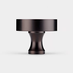 Puede incluir: Un pomo para mueble de color marr&oacute;n oscuro con una parte superior cil&iacute;ndrica y una base acampanada en forma de pedestal. El herraje presenta un acabado mate liso y una construcci&oacute;n s&oacute;lida, dise&ntilde;ado para fijarse a puertas o cajones.