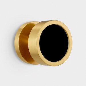 Pode incluir: Uma maçaneta de porta dourada com um inserto circular preto. A maçaneta é redonda e tem um acabamento liso e polido.