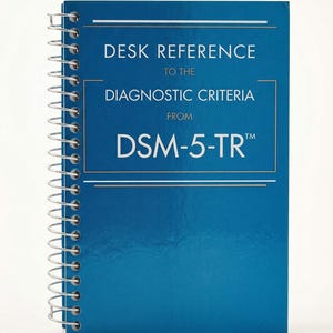 May include: A blue spiral-bound desk reference book with white text that reads: DESK REFERENCE TO THE DIAGNOSTIC CRITERIA FROM DSM-5-TR. The cover features a metallic finish with thin white horizontal lines framing the title and subtitle text.