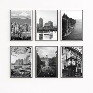 May include: A set of six black and white framed wall art prints featuring various cityscapes and landmarks, including a skyline with mountains, a domed building, a coastal road, a park bench, a suspension bridge, and a street clock tower.
