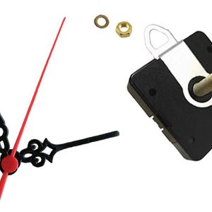 May include: Clock parts, including a black clock movement, black and red clock hands, a brass nut, and a brass washer. The clock hands are black with decorative designs. The second hand is red. The clock movement is square and black.