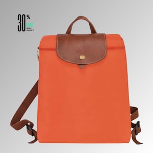 May include: A bright orange backpack featuring a brown textured flap with a gold-tone snap closure, a top handle, and adjustable brown shoulder straps. The text 30% OFF ON ALL PRODUCTS is visible in the upper left corner of the image.