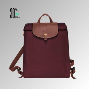 Puede incluir: Una mochila de nailon color burdeos con una solapa de cuero marrón con cierre de botón a presión dorado, un asa superior y correas ajustables. El texto 30% OFF ON ALL PRODUCTS es visible en la esquina superior izquierda de la imagen.