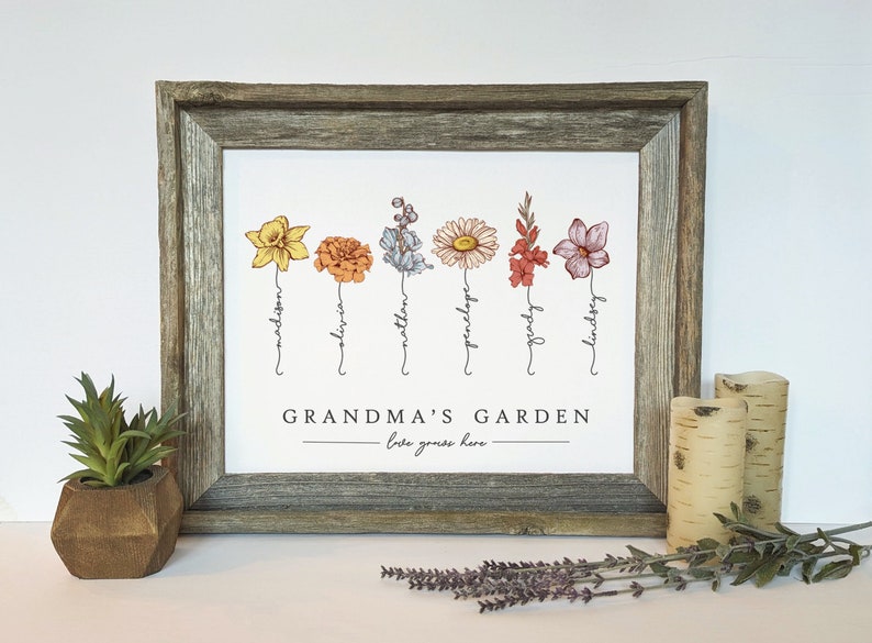 May include: A framed print with a white background featuring a line of six colourful flowers with names written underneath each flower. The names are Madison, Olivia, Matthew, Penelope, Grady, and Lindsey. The text at the bottom of the print reads "Grandma's Garden - love grows here - "